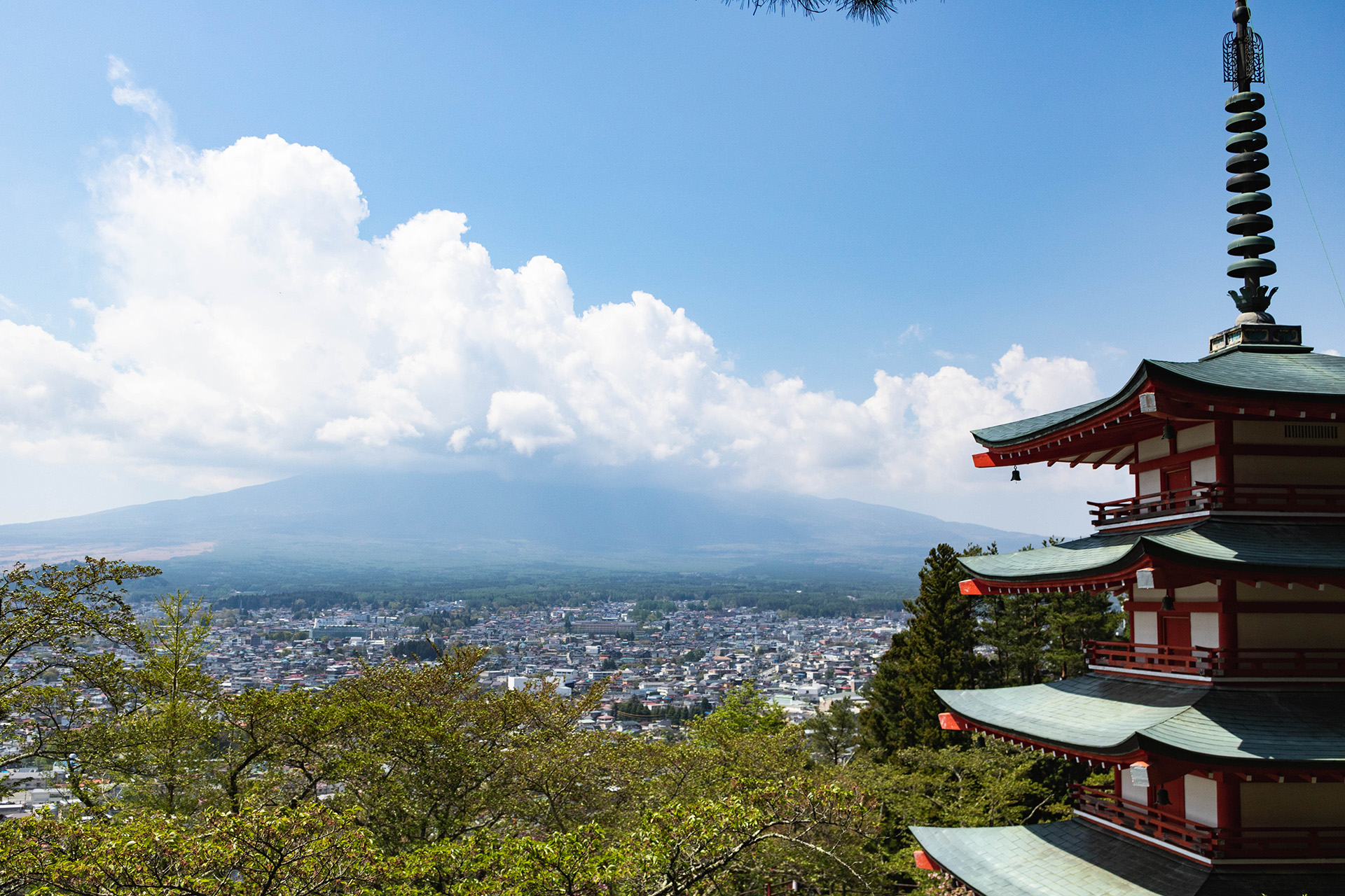 Pagoda with clouds covering a mountain in the background and a city below.